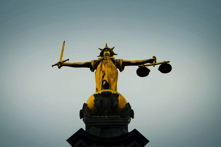 Perched atop the Family Court building, the golden statue of Lady Justice holds a sword and scales aloft against a gray sky, embodying both balance and strength.
