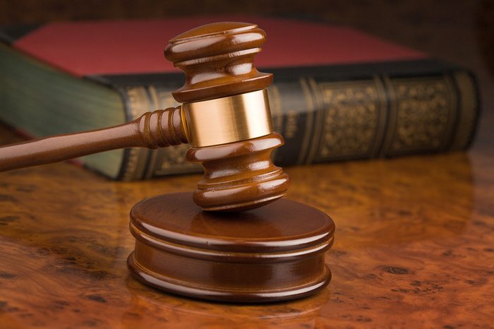 A wooden judge's gavel rests on its sound block with a large legal book in the background, evoking the authority of a Morgantown family court judge deliberating on matters of guilt and justice.